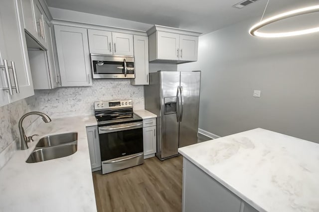 kitchen with light countertops, appliances with stainless steel finishes, gray cabinets, and a sink