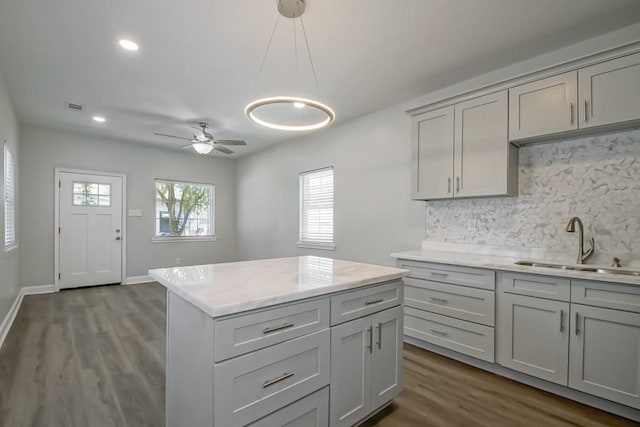 kitchen featuring light countertops, visible vents, decorative backsplash, gray cabinetry, and a kitchen island