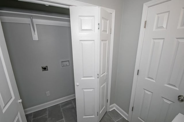 laundry area featuring laundry area, dark tile patterned floors, baseboards, and electric dryer hookup