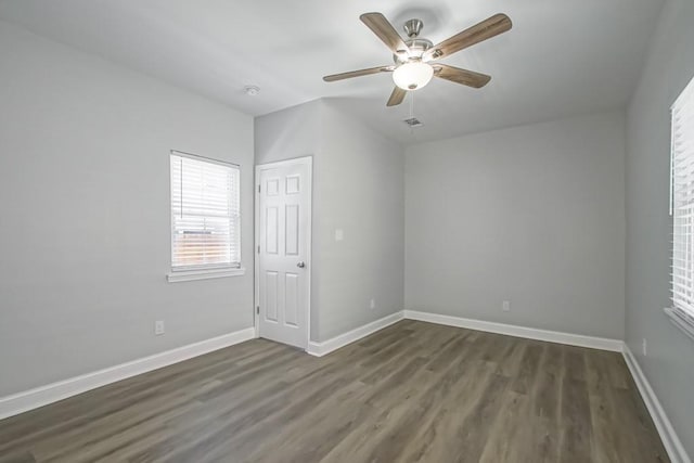 unfurnished room with dark wood-type flooring, ceiling fan, and baseboards