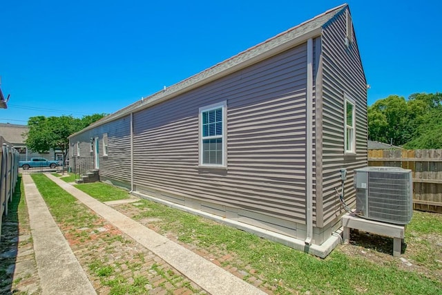 view of side of home featuring cooling unit and fence