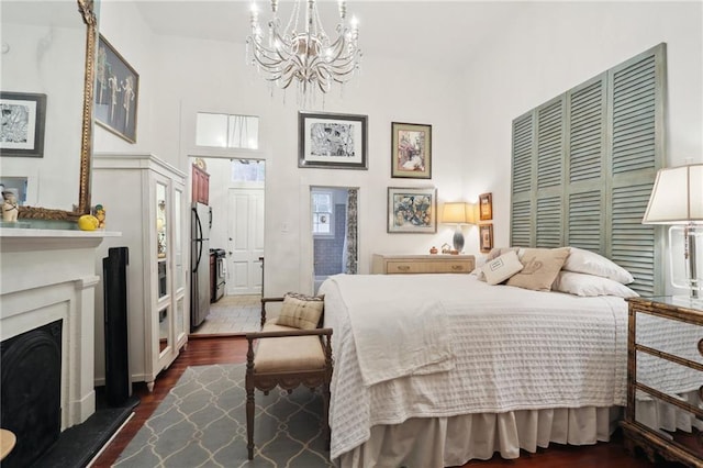 bedroom featuring an inviting chandelier, stainless steel refrigerator, dark hardwood / wood-style flooring, and a closet