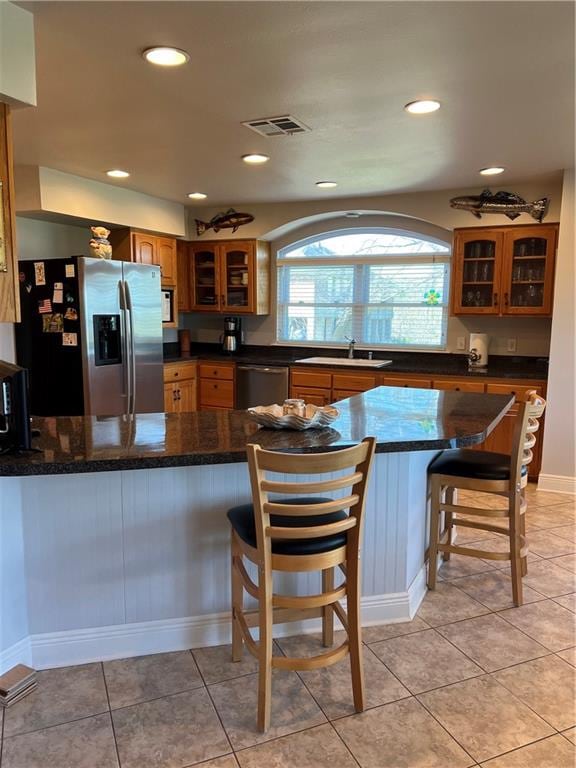 kitchen featuring stainless steel appliances, sink, light tile flooring, and a kitchen bar