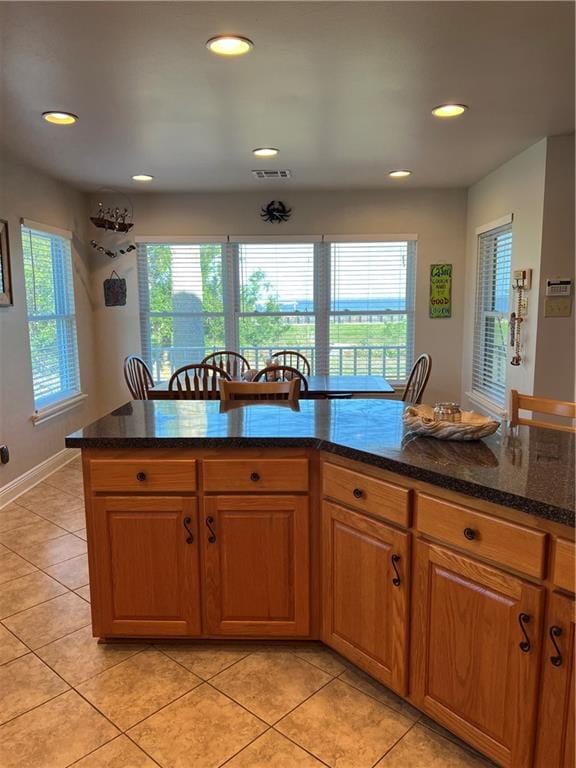 kitchen featuring a healthy amount of sunlight, dark stone countertops, and light tile floors