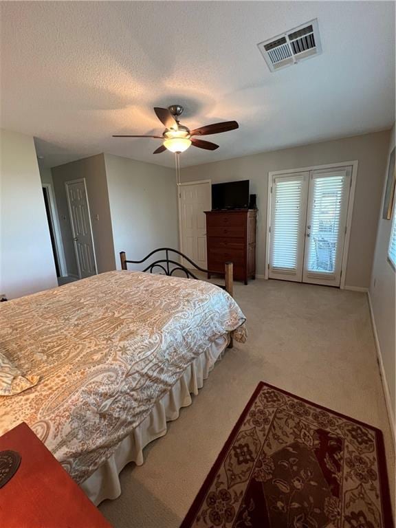 carpeted bedroom with a textured ceiling, ceiling fan, and french doors