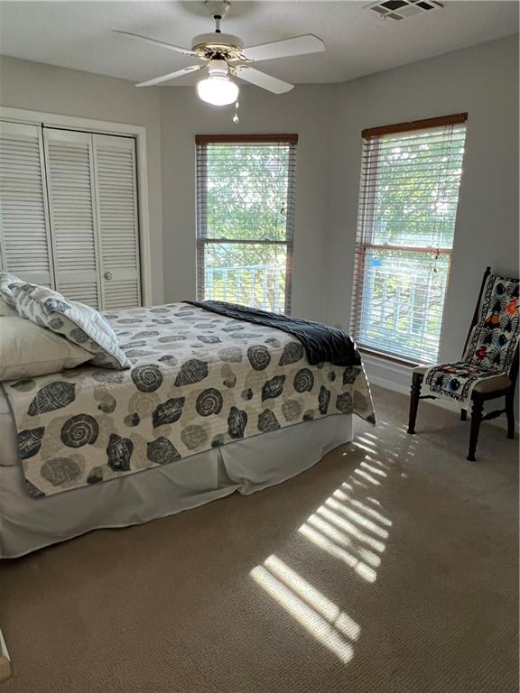 bedroom with ceiling fan, a closet, and carpet flooring