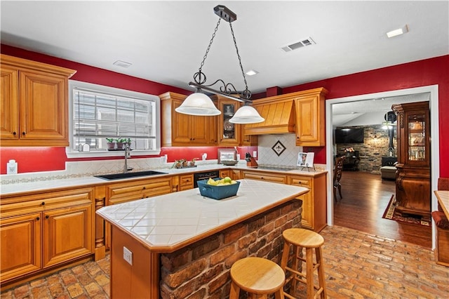 kitchen with tasteful backsplash, custom exhaust hood, tile counters, a center island, and sink