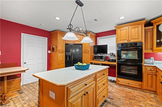 kitchen featuring visible vents, brick floor, tile counters, decorative light fixtures, and black appliances