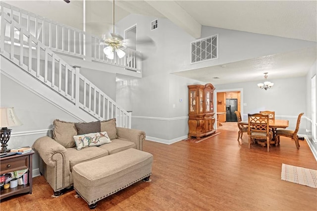 living area with wood finished floors, visible vents, high vaulted ceiling, and stairway
