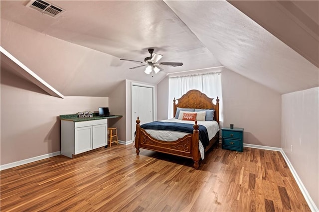 bedroom with lofted ceiling, light wood finished floors, visible vents, a ceiling fan, and baseboards