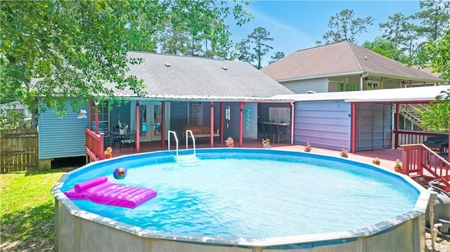 pool featuring a wooden deck, french doors, stairs, and fence