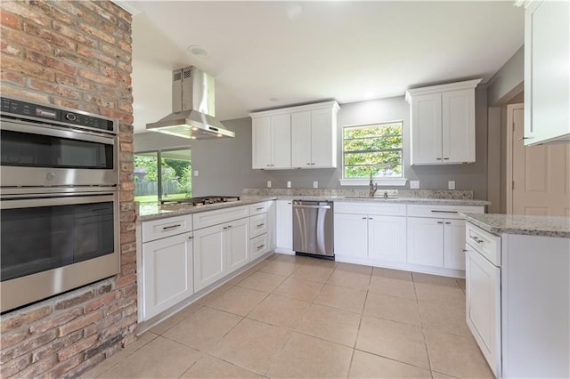 kitchen with appliances with stainless steel finishes, white cabinetry, wall chimney exhaust hood, and sink