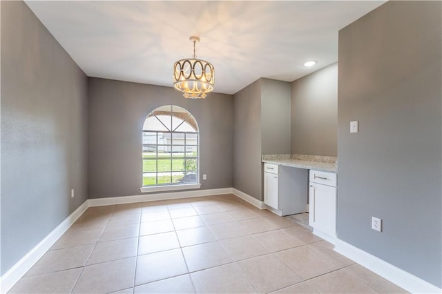 empty room featuring light tile patterned flooring, built in desk, and a chandelier