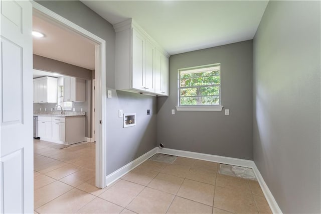 laundry room featuring hookup for an electric dryer, light tile patterned floors, cabinets, and sink