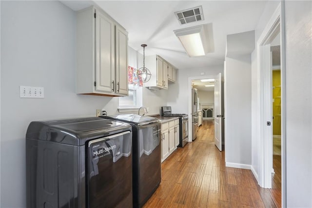 205 Stonehaven Dr, Belle Chasse, LA 70037 - washroom with hardwood / wood-style flooring, washing machine and dryer, and cabinets