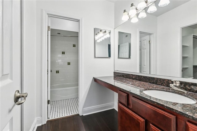 bathroom with a chandelier, vanity, hardwood / wood-style floors, and tiled shower / bath combo