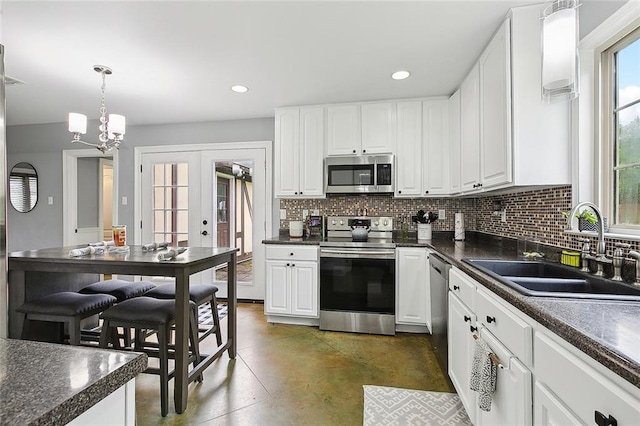 kitchen featuring pendant lighting, stainless steel appliances, sink, and white cabinetry