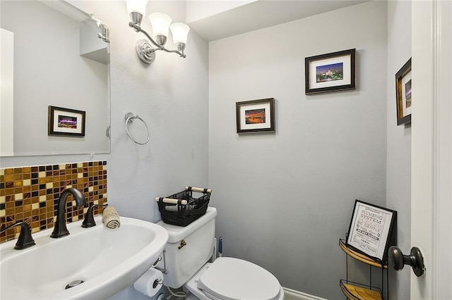 bathroom featuring toilet, sink, and tasteful backsplash