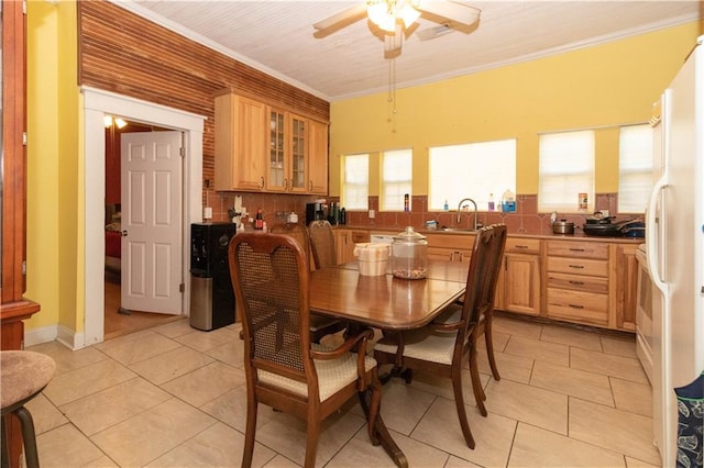 tiled dining space with ceiling fan, crown molding, and sink