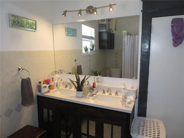 bathroom featuring tile walls, large vanity, toilet, and dual sinks