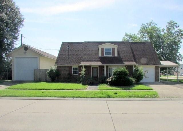 cape cod-style house with a front yard, a garage, and a carport