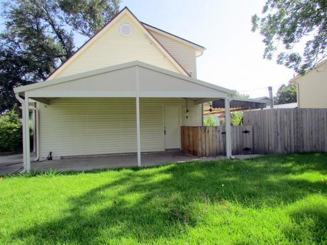 rear view of house featuring a lawn and a carport