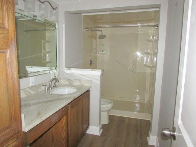 bathroom featuring a shower, wood-type flooring, vanity, and toilet