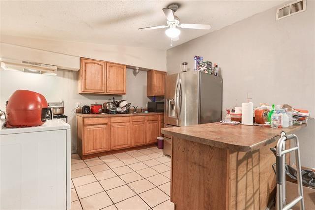 kitchen with ceiling fan, kitchen peninsula, vaulted ceiling, washer / dryer, and light tile patterned floors