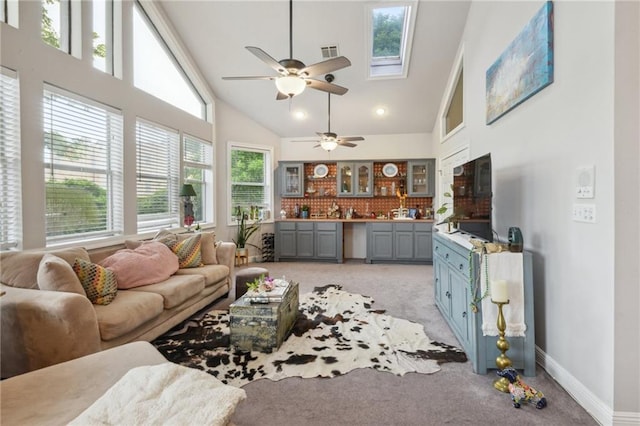 living room featuring plenty of natural light, light colored carpet, high vaulted ceiling, and a skylight