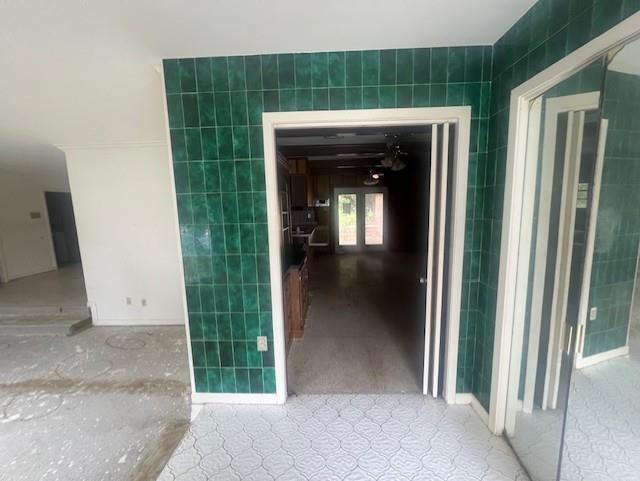 hall featuring light tile patterned floors and tile walls