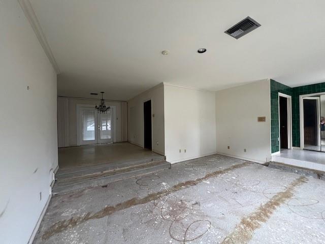 unfurnished living room with an inviting chandelier and french doors