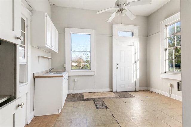 interior space featuring white cabinets, sink, ceiling fan, and light parquet flooring