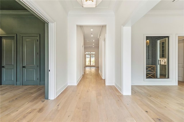 corridor with light hardwood / wood-style floors and ornamental molding