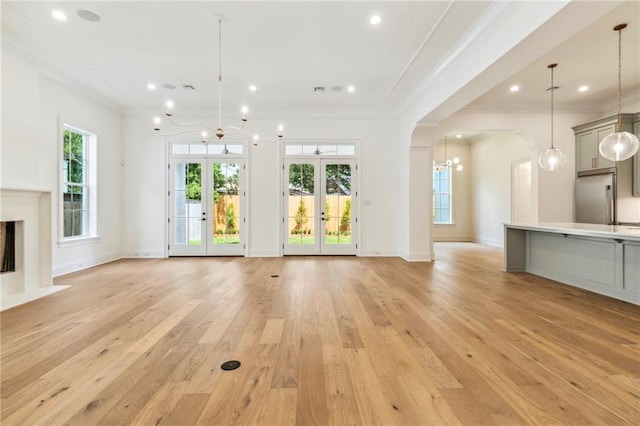 unfurnished living room with light hardwood / wood-style floors, french doors, and crown molding