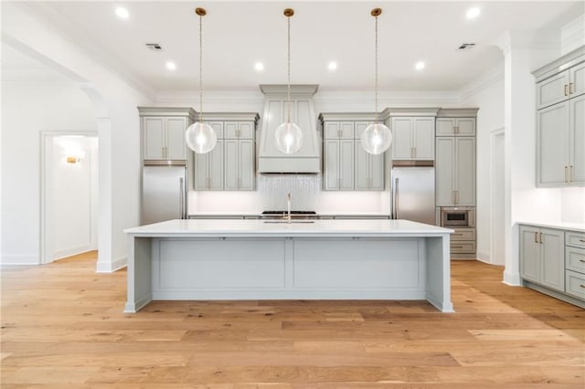 kitchen with built in appliances, light hardwood / wood-style flooring, hanging light fixtures, and gray cabinets