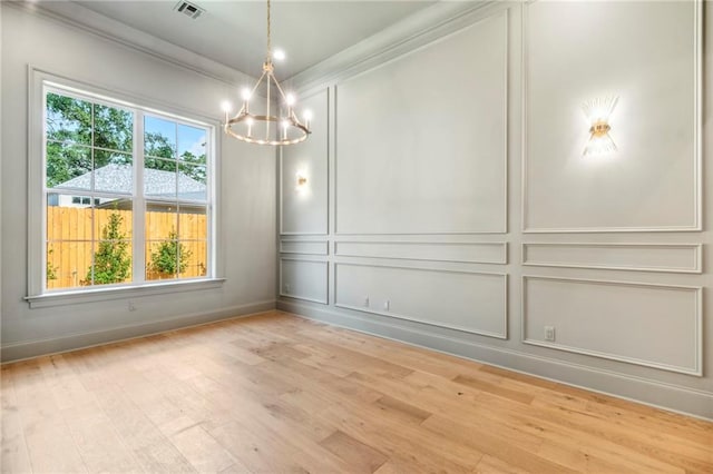 unfurnished room featuring ornamental molding, a healthy amount of sunlight, light wood-type flooring, and a chandelier