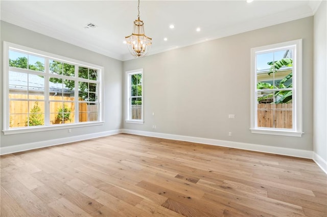 empty room featuring an inviting chandelier, light wood-type flooring, and ornamental molding