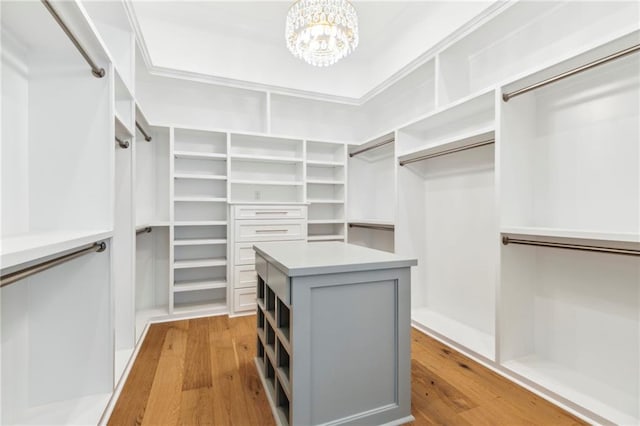 walk in closet with light wood-type flooring and a chandelier