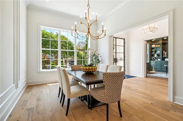 dining area with plenty of natural light, an inviting chandelier, light hardwood / wood-style flooring, and ornamental molding