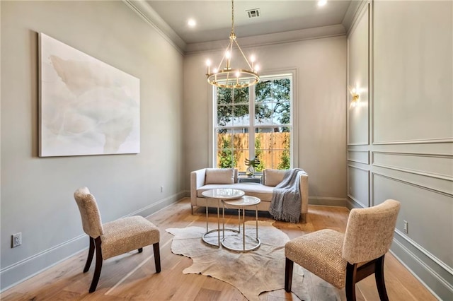 living area featuring ornamental molding, a notable chandelier, and light hardwood / wood-style floors