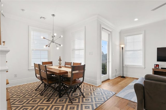 dining area with light hardwood / wood-style floors, crown molding, and an inviting chandelier