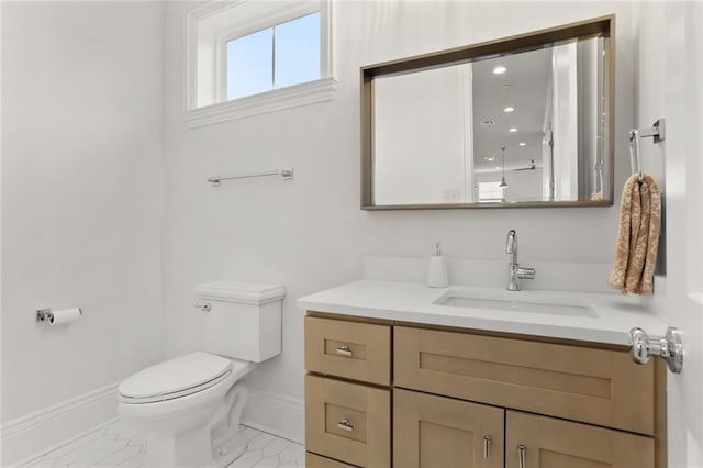 bathroom featuring toilet, baseboards, and vanity