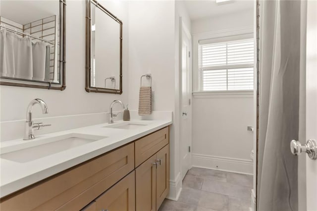 full bath featuring a sink, baseboards, and double vanity