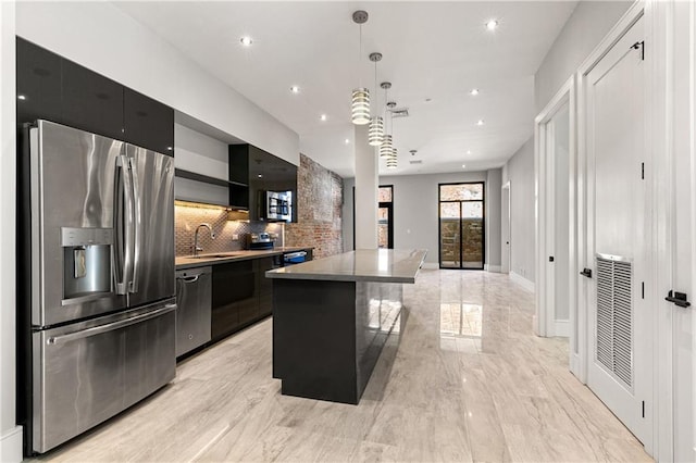 kitchen featuring a center island, sink, stainless steel appliances, backsplash, and decorative light fixtures