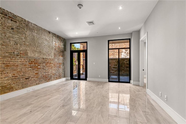 unfurnished room with brick wall and french doors