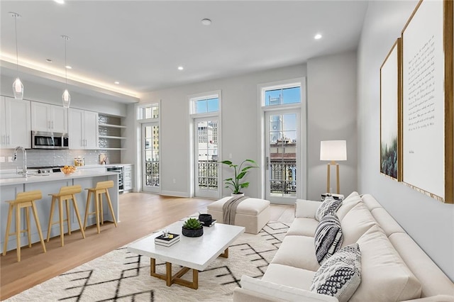 living room with wine cooler, light hardwood / wood-style flooring, and sink