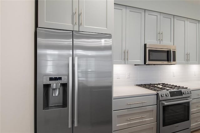 kitchen with gray cabinetry, decorative backsplash, and stainless steel appliances