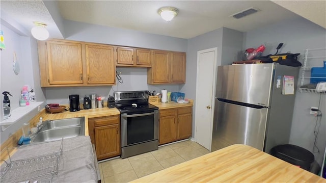 kitchen featuring appliances with stainless steel finishes, light tile patterned floors, and sink