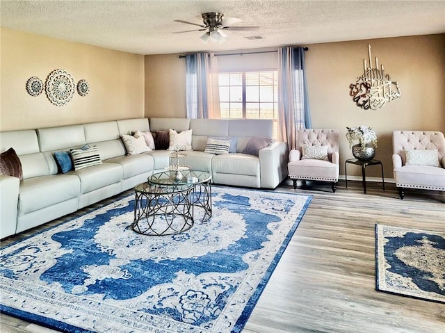 living room featuring ceiling fan, wood-type flooring, and a textured ceiling