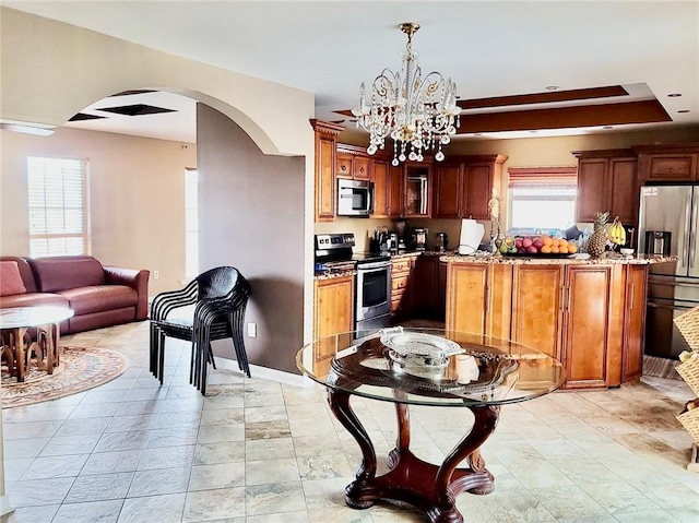 kitchen featuring decorative light fixtures, a notable chandelier, stainless steel appliances, and a wealth of natural light